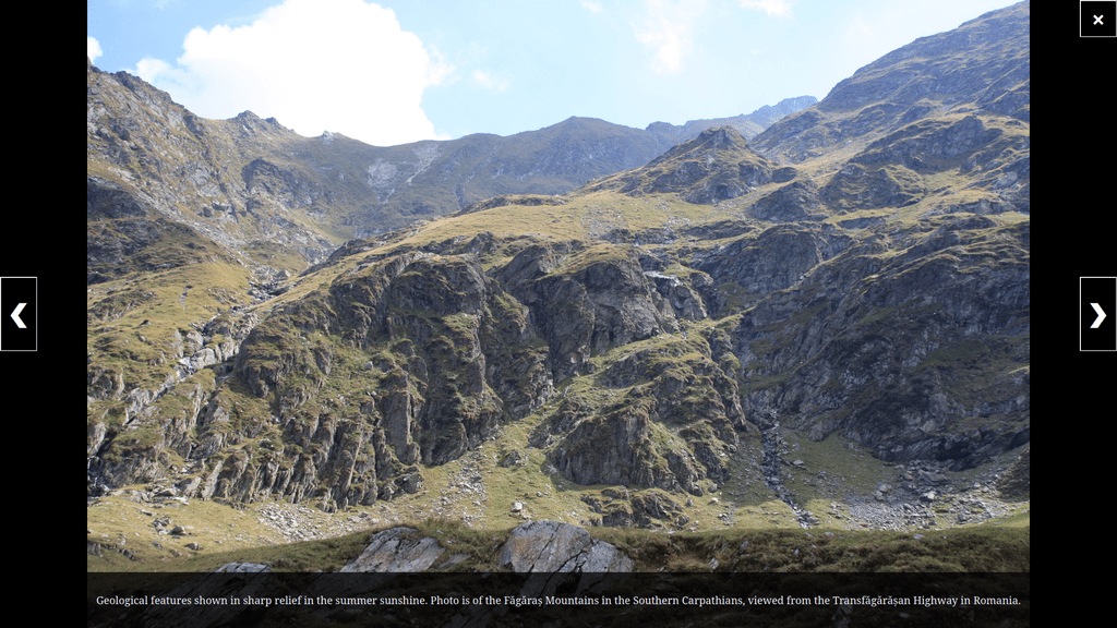 A fullscreen slideshow view of summer noontime sunshine casting mountain features in sharp relief with short grass, crags, and eroded runnels evident.